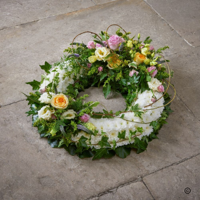 Garden Wreath - A natural open wreath combining soft pink, cream and peach tones with abundant greenery and delicate trailing details.