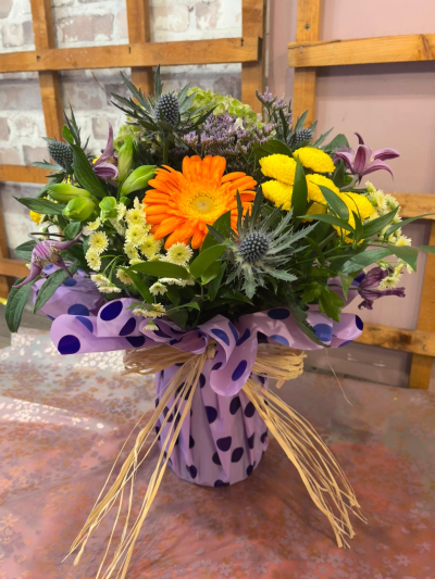Cheerful Charm - A vibrant arrangement combining orange, yellow and purple tones with abundant fresh greenery, handcrafted by Daisy Chain Florist in Scunthorpe.
